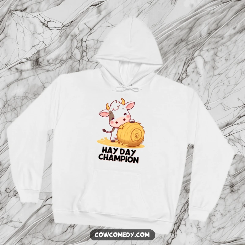 Funny cozy hoodie showcasing a playful cow nudging a rolling ball of hay, perfect for warm comfort and humorous vibes.