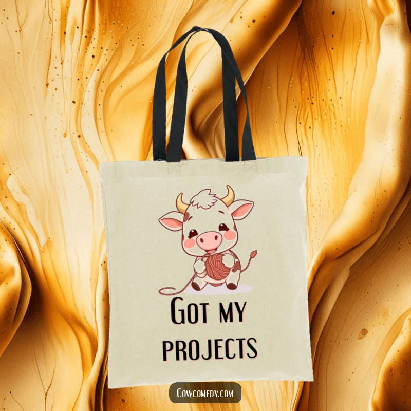 Funny tote bag print of an excited cow joyfully nudging a ball of yarn with its nose, perfect for carrying essentials with a humorous touch.